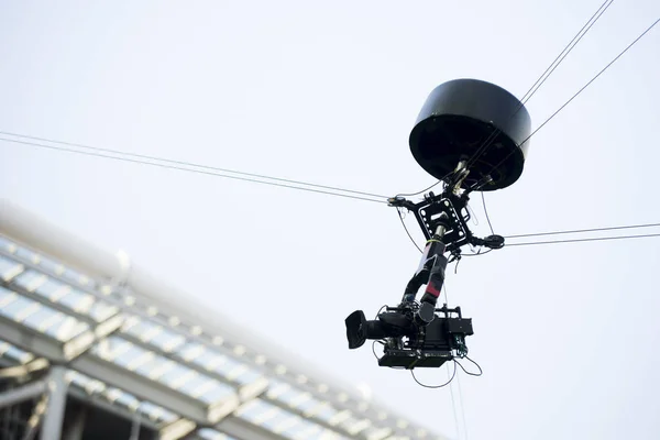A television camera hangs on cables for football or a concert