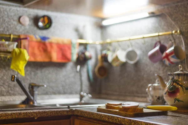 Ahşap masada kesme tahtasında sosis, mutfak bıçağı, ekmek parçaları. 