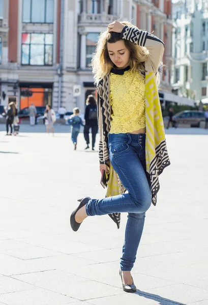 Genç güzel kız topuklu ayakkabısını görünüyor. Cadde boyunca yürüyüş.