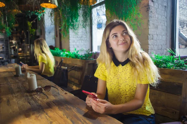 Bir telefon ile güzel kız bir kafede oturuyor