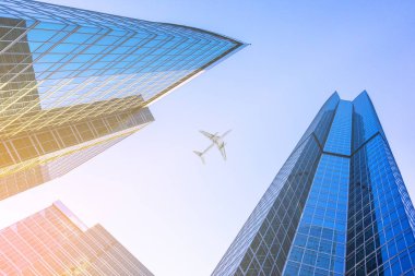 İş gökdelenler, yüksek binalar üzerinde uçan uçak. Güneş ışığı 