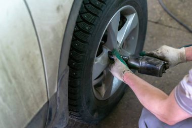 Tamir istasyonunda kaldırılan otomobilin vidaları vidalanmış veya sökülmüş araba tamircisi