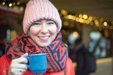 Fularlı güzel kadın Noel pazarı üzerinde mulled şarap içer