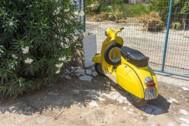 Yellow scooter parked near the fence