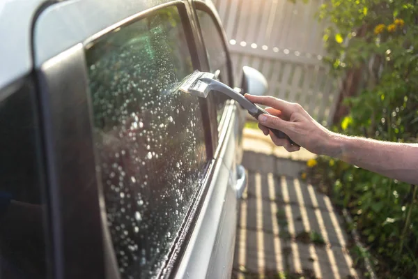 worker washing the car window with a scraper