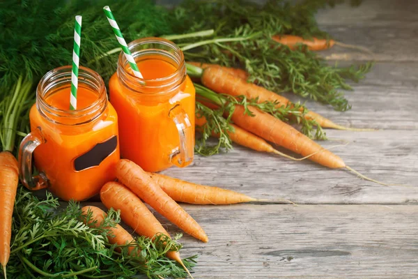 Taze havuç ve havuç suyu bahçe ahşap tablo. Sebze vitaminler Keratin. Doğal organik havuç ahşap arka plan üzerinde yatıyor.