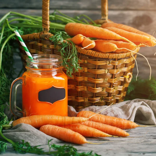 Fresh Carrot and carrot juice on Wooden Table in Garden. Vegetables Vitamins Keratin. Natural Organic Carrot lies on Wooden background.