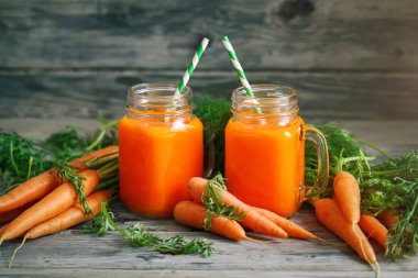 Taze havuç ve havuç suyu bahçe ahşap tablo. Sebze vitaminler Keratin. Doğal organik havuç ahşap arka plan üzerinde yatıyor.