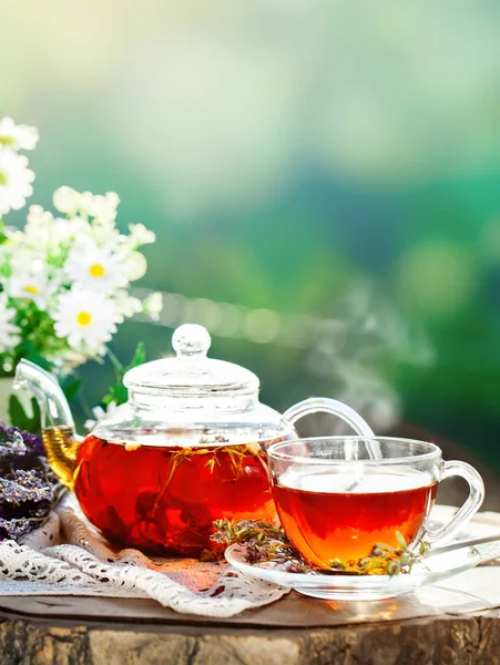 Cup met hete thee met munt en een tijm op een houten tafel in een zomertuin. Selectieve aandacht, — Stockfoto