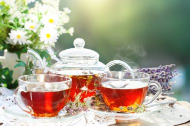 Fincan sıcak çay nane ve yaz bahçesinde ahşap bir masa üzerinde bir kekik ile. Seçici odak,