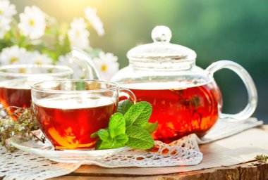 Fincan sıcak çay nane ve yaz bahçesinde ahşap bir masa üzerinde bir kekik ile.