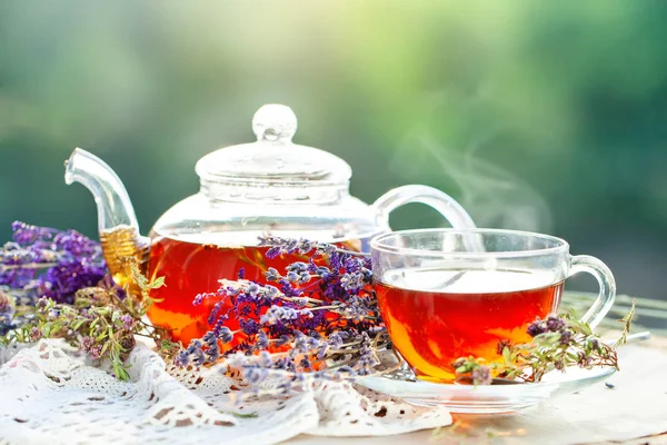 Cup met hete thee met munt en een tijm op een houten tafel in een zomertuin. Selectieve aandacht, — Stockfoto