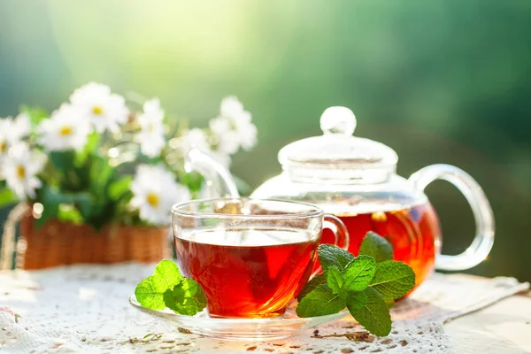 Cup met hete thee met munt en een tijm op een houten tafel in een zomertuin. — Stockfoto