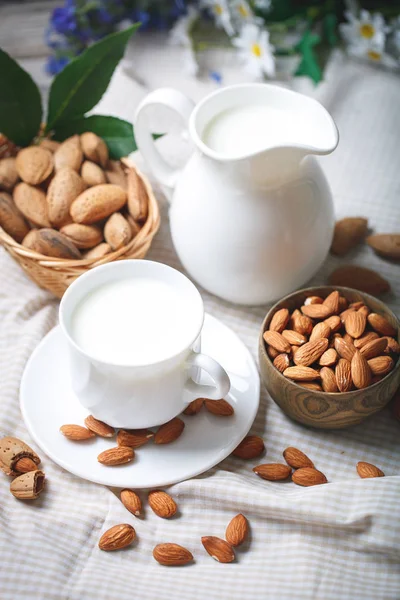 Almond and almond milk on a wooden table in the summer garden. Useful food.