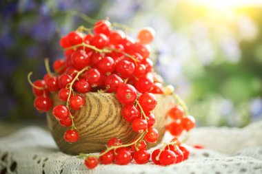 Bahçedeki ahşap bir masa üzerinde olgun kırmızı kuş üzümü.