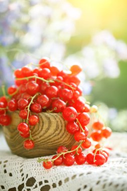 Bahçedeki ahşap bir masa üzerinde olgun kırmızı kuş üzümü.