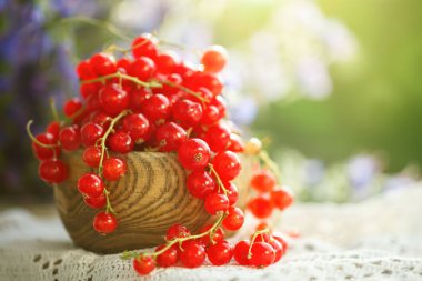 Bahçedeki ahşap bir masa üzerinde olgun kırmızı kuş üzümü.