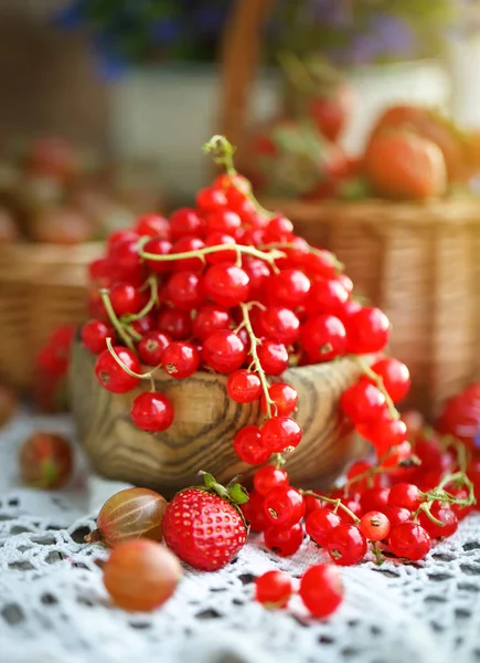 Bahçedeki ahşap bir masa üzerinde olgun kırmızı kuş üzümü.
