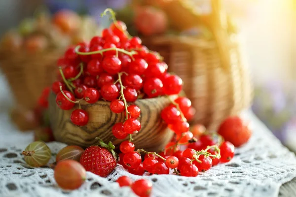 Bahçedeki ahşap bir masa üzerinde olgun kırmızı kuş üzümü.