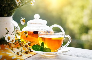 Fincan sıcak çay nane ve yaz bahçesinde ahşap bir masa üzerinde bir kekik ile.