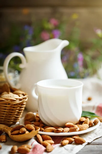 Мигдальне та мигдальне молоко на дерев'яному столі в літньому саду. Корисна їжа . — стокове фото