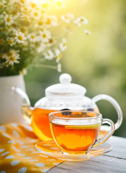 Cup met hete thee met munt en een tijm op een houten tafel in een zomertuin. — Stockfoto