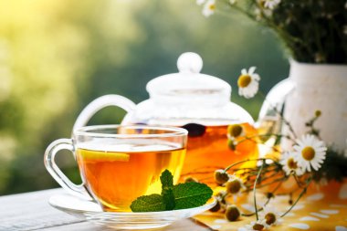 Fincan sıcak çay nane ve yaz bahçesinde ahşap bir masa üzerinde bir kekik ile.