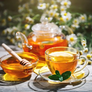 Fincan sıcak çay nane ve yaz bahçesinde ahşap bir masa üzerinde bir kekik ile.