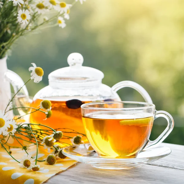 Cup met hete thee met munt en een tijm op een houten tafel in een zomertuin. — Stockfoto