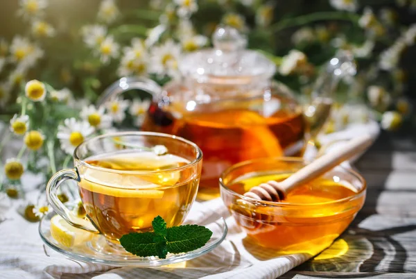 Cup met hete thee met munt en een tijm op een houten tafel in een zomertuin. — Stockfoto