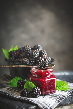 Olgun böğürtlen ve böğürtlen reçeli ahşap bir masa üzerinde. Koyu arka plan.