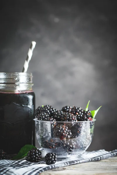 Ripe blackberry and blackberry juice on a wooden table. Dark background. — Stock Photo, Image
