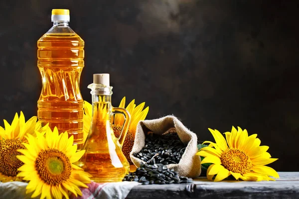 Photo rapprochée de tournesols et d'huile de tournesol avec des graines sur une table en bois. Concept biologique et biologique du produit . — Photo