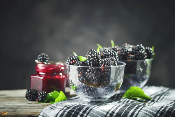 Ripe blackberry and blackberry jam on a wooden table. Dark background. — Stock Photo, Image