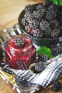 Olgun böğürtlen ve böğürtlen reçeli ahşap bir masa üzerinde. Koyu arka plan.
