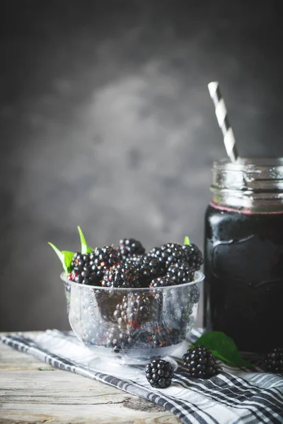 잘 익은 블랙베리 그리고 나무 테이블에 검은 딸기 주스. 어두운 배경. — 스톡 사진