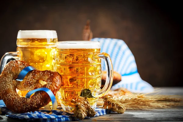 Canecas de cerveja e pretzels em uma mesa de madeira. Oktoberfest. Festival da cerveja . — Fotografia de Stock