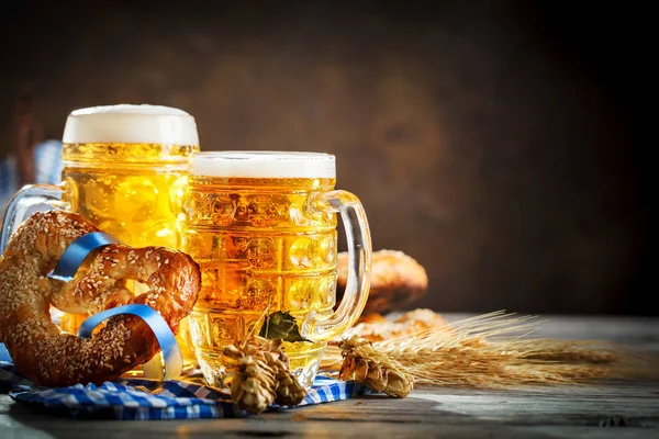 Canecas de cerveja e pretzels em uma mesa de madeira. Oktoberfest. Festival da cerveja . — Fotografia de Stock