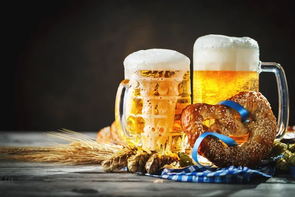Tazas de cerveza y pretzels en una mesa de madera. Oktoberfest. Festival de la cerveza . — Foto de Stock