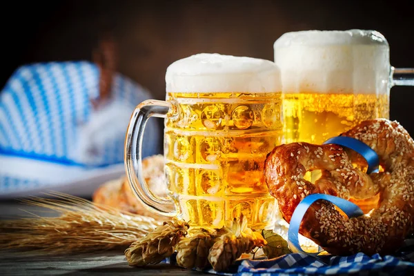 Canecas de cerveja e pretzels em uma mesa de madeira. Oktoberfest. Festival da cerveja . — Fotografia de Stock