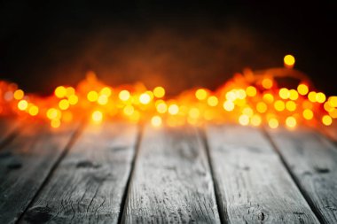 Mutlu Noeller ve mutlu yeni yıl. Ahşap masa Noel ışıkları arka plan üzerinde. Bokeh. Seçici odak. Arka plan kopya alanı ile.