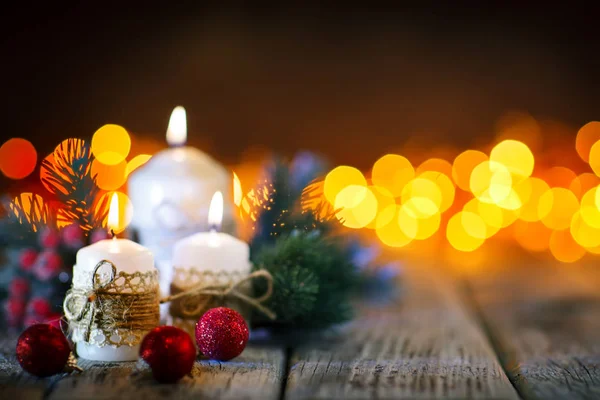 God jul och gott nytt år. Ljus och jul leksaker på ett träbord på bakgrunden av en krans. Bokeh. Selektivt fokus. Bakgrund med kopia utrymme. — Stockfoto