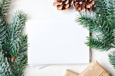 Mutlu Noeller ve mutlu yeni yıl. Mockup kartpostal ve beyaz arka plan üzerinde bir Noel ağacı dalları ile. Arka plan kopya alanı ile. Üstten görünüm. Noel arka plan. Yatay.