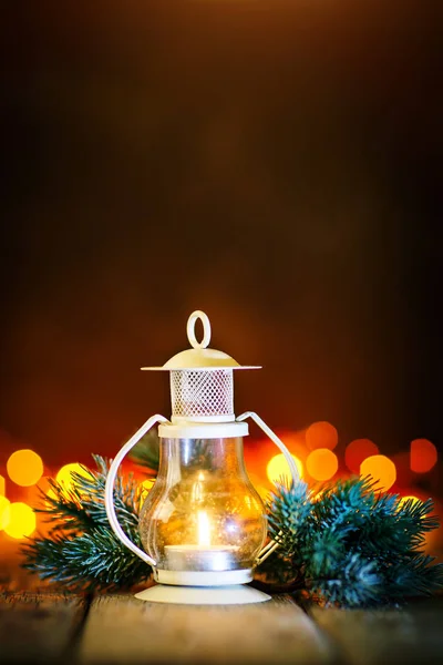 Buon Natale e felice anno nuovo. Candela e giocattoli di Natale su un tavolo di legno sullo sfondo di una ghirlanda. Bokeh. Concentrazione selettiva. Sfondo con spazio di copia . — Foto Stock