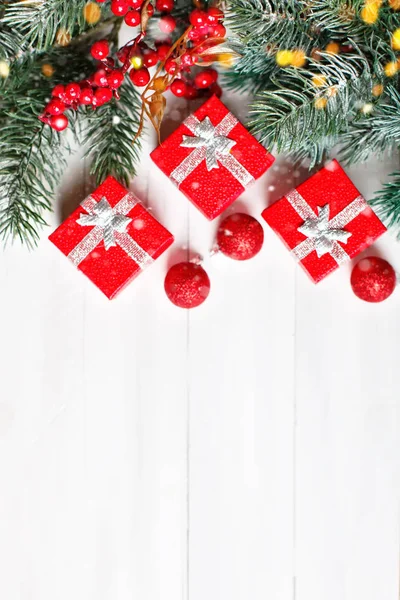 God jul och gott nytt år. Gåvor och fir-trädgrenar på en vit träbord. Selektivt fokus. Jul bakgrund. Lodrät. Ovanifrån. — Stockfoto