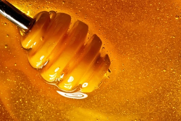 Honey with gold color flows down from a spoon, on a dark background. Healthy eating. Diet. Selective focus. Background with copy space.