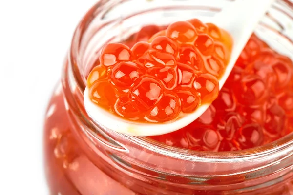 Kırmızı havyar beyaz zemin üzerine kaşık ile cam kavanoza. Deniz ürünleri. Sağlıklı beslenme. Diyet. Seçici odak.