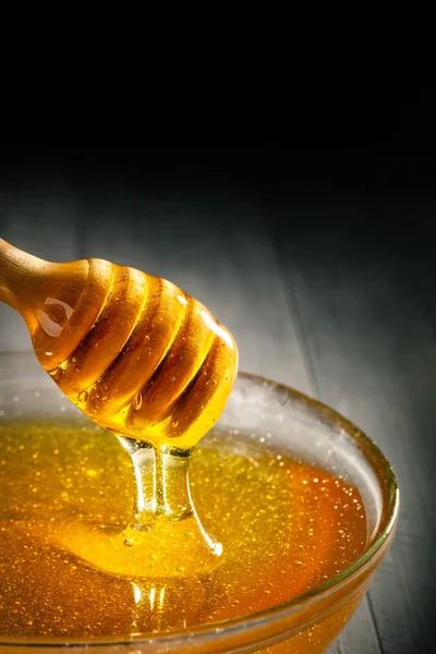 Le miel avec la couleur d'or coule vers le bas d'une cuillère. Concept d'alimentation saine. Une saine alimentation. Régime alimentaire. Concentration sélective. Arrière plan avec espace de copie . — Photo