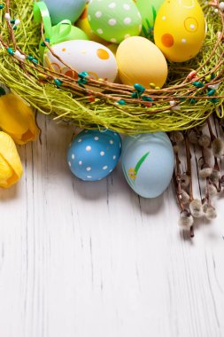 Mutlu Paskalyalar. Paskalya arkaplanını tebrik ederim. Paskalya yumurtaları ve çiçekler. Kopya alanı olan bir arkaplan. Seçici odaklanma. Üst görünüm.