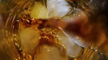 Viski buzlu bir bardağa döküldü. Karanlık arka planda. Üst görünüm.